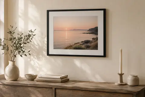 Cadre photo mural noir avec passe-partout blanc, accroché sur un mur crème dans un intérieur chaleureux.
