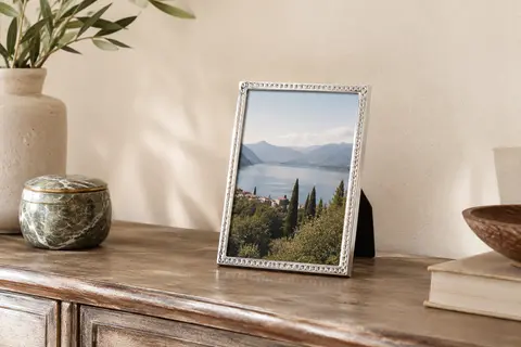 Cadre photo Bergamo argenté à motif à pois, posé sur une console devant un mur crème.
