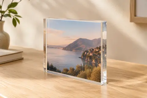 Bloc photo plat en acrylique transparent, posé debout sur un bureau en bois clair, avec une photo de paysage prise au centre.