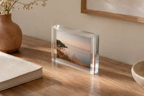 Cadre photo transparent double face posé sur un bureau, avec une image allongée visible entre ses blocs en acrylique.